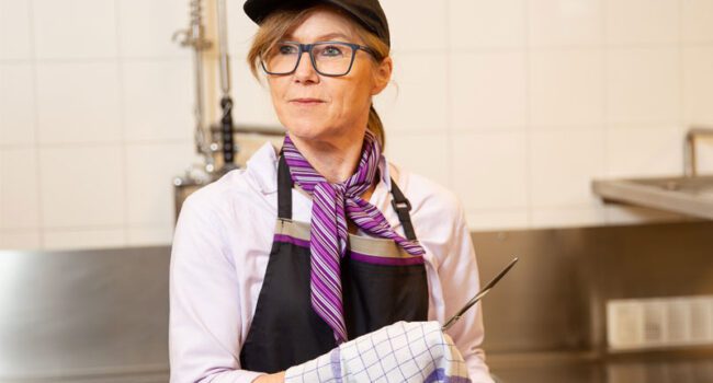 Kitchen helper washing dishes in a safe working environment with slip-resistant and safety shoes