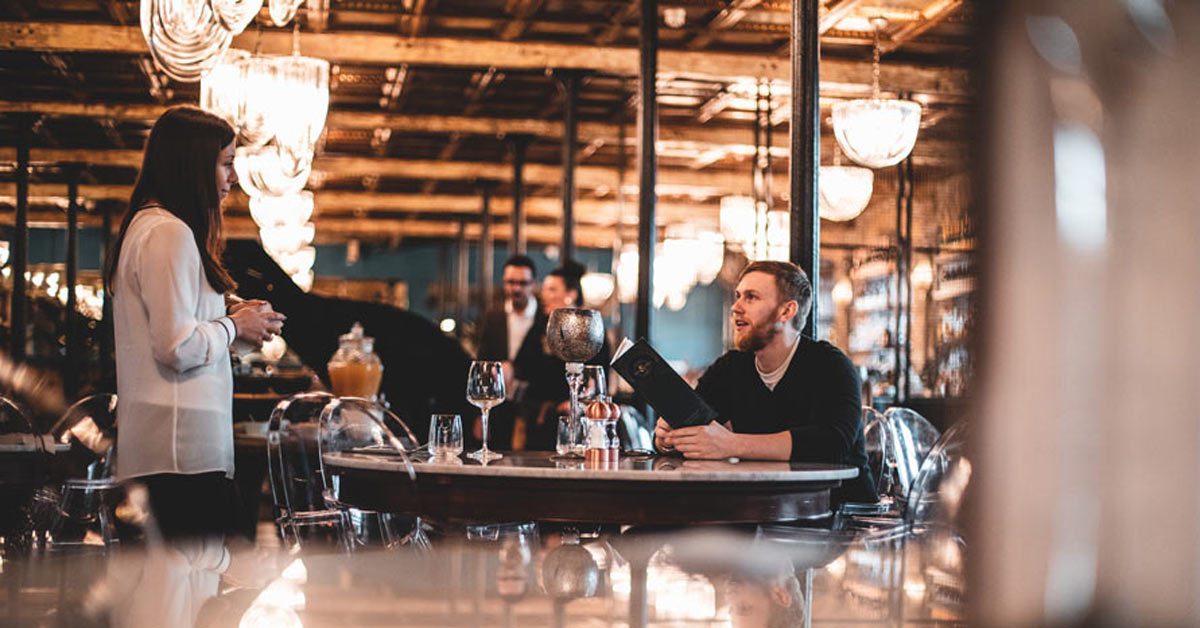 Waitress wearing comfortable restaurant shoes serving man sitting at table