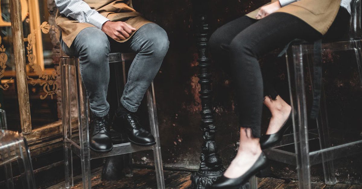 Restaurant workers sitting on bar stools at a table wearing different Shoes For Crews styles all in the colour black