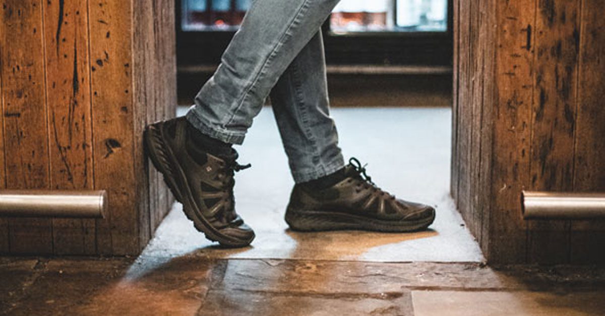 Restaurant server leaning against gap in bar wearing black, lightweight, breathable work shoes from Shoes For Crews