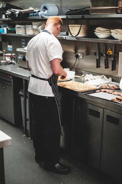 Chef wearing black, water-resistant kitchen clogs while preparing pastries at counter