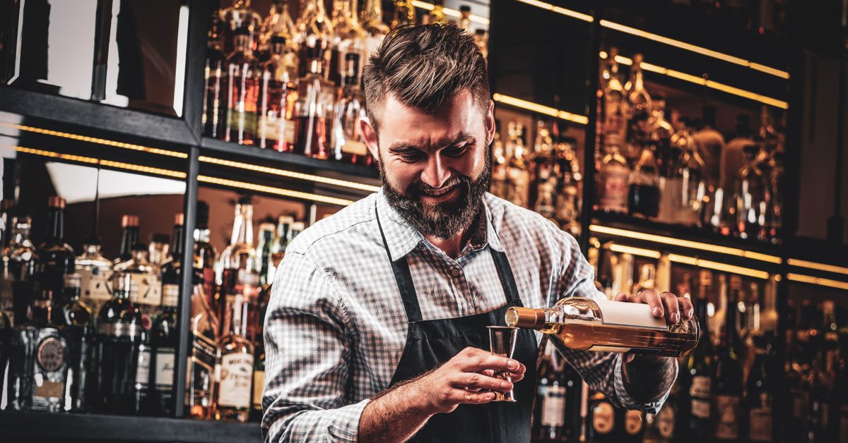 Smiling bartender preparing and pouring cocktails for customers