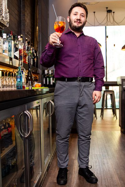 Bartender raising mixed drink with straw in air