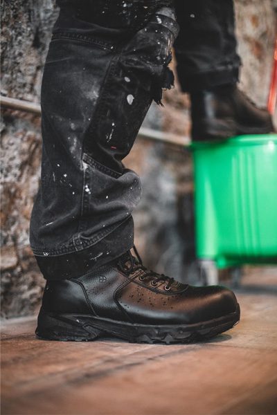 Worker propping foot up on green bucket wearing insulated work boots