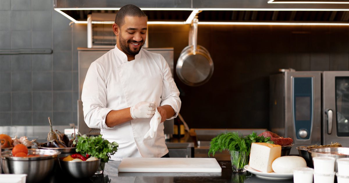 Chef in kitchen putting on protective gloves before beginning to prepare food