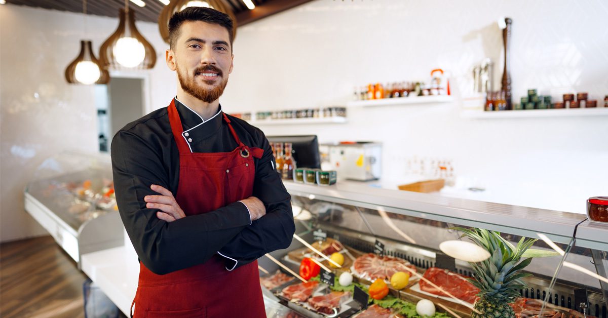 Boucher devant une vitrine de boucherie de supermarché