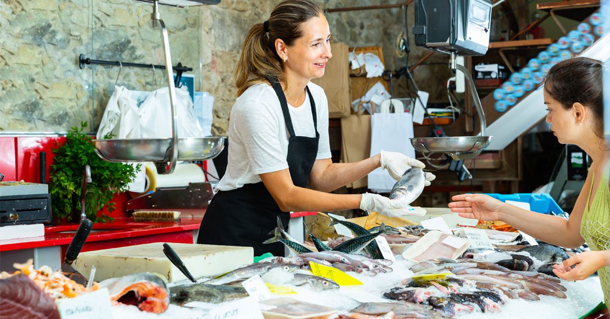 Employée de poissonnerie proposant un poisson à une cliente