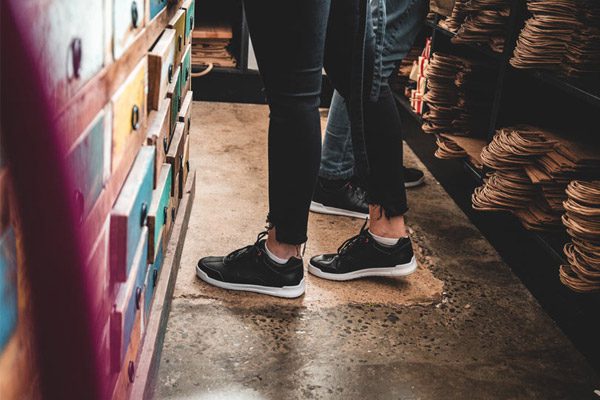 Two store assistants standing behind the counter wearing black and white slip-resistant Shoes For Crews footwear