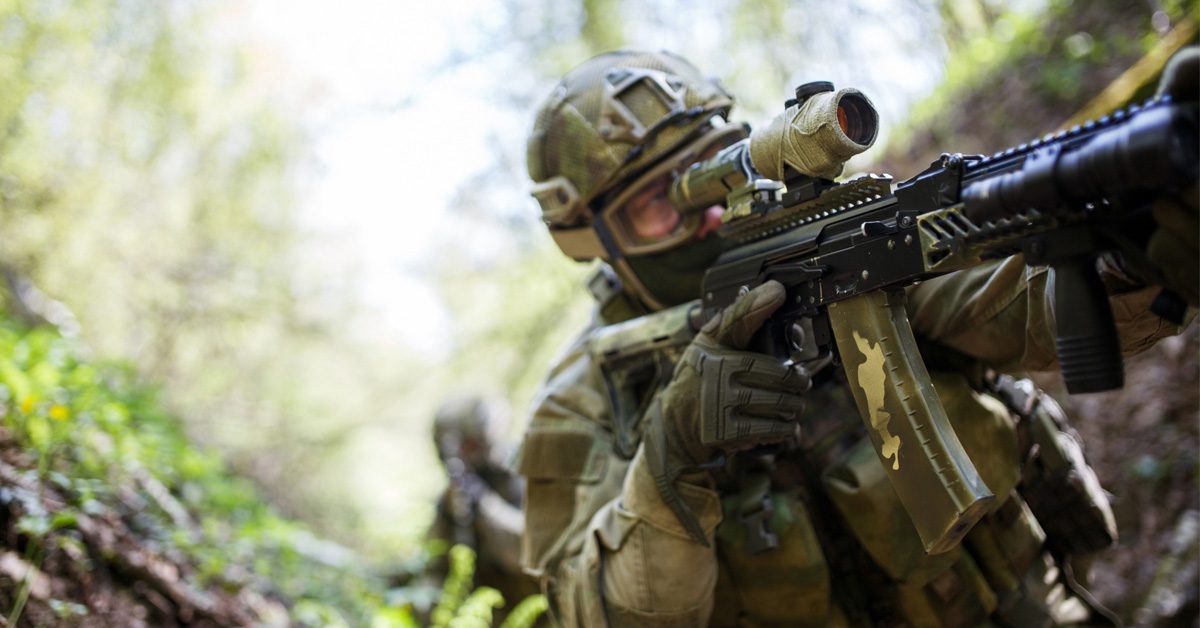 army soldier in tactical boots getting ready to shoot his target in the forest