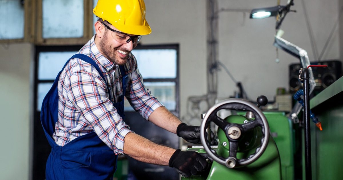 Worker wearing yellow hardhat and safety glasses while operating wheeled machinery