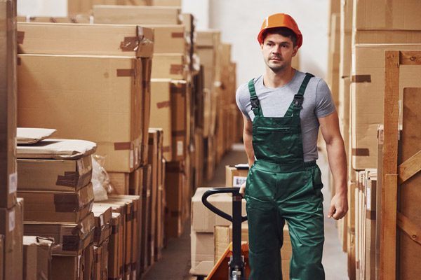 Worker pulling boxes with trolley to assist with manual handling task