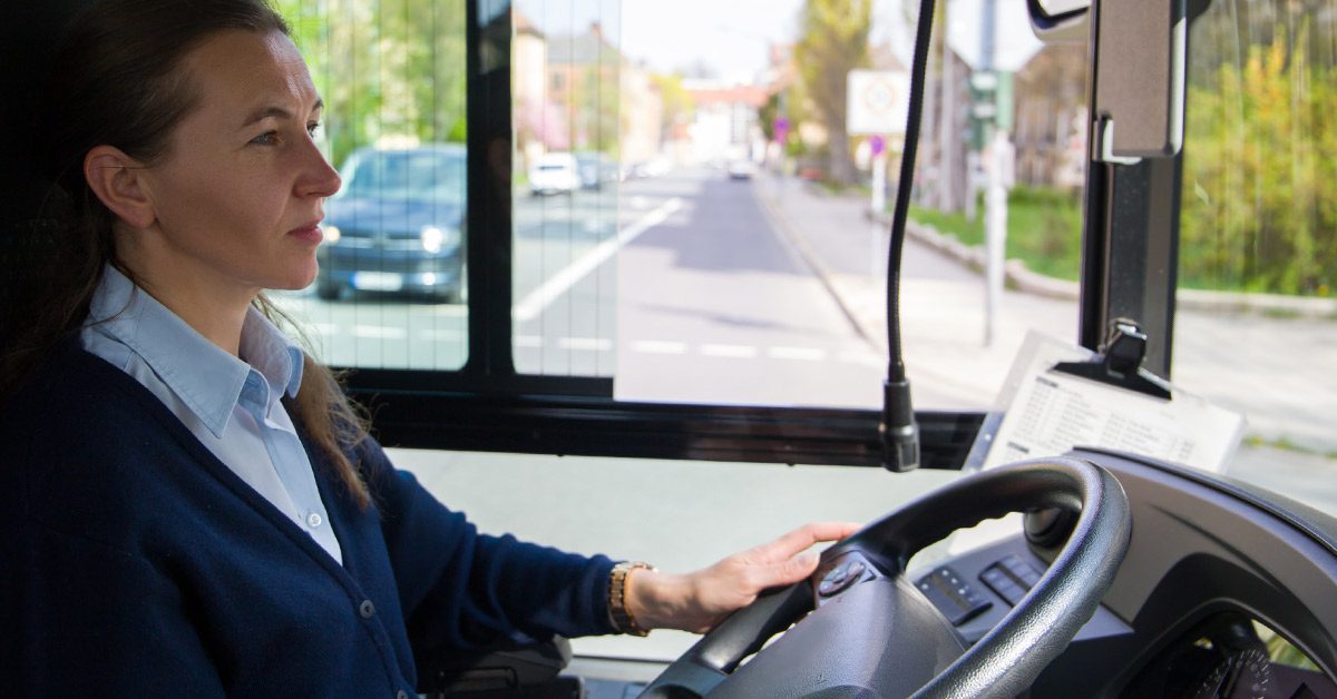 A female bus driver in uniform driving a bus