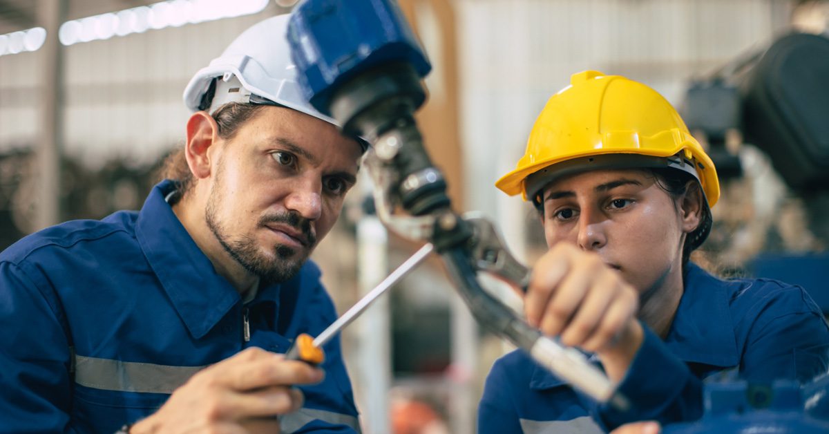 Dos profesionales realizan tareas de mantenimiento en una máquina industrial 