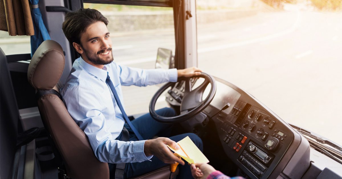 Smiling bus driver taking ticket from boarding passenger