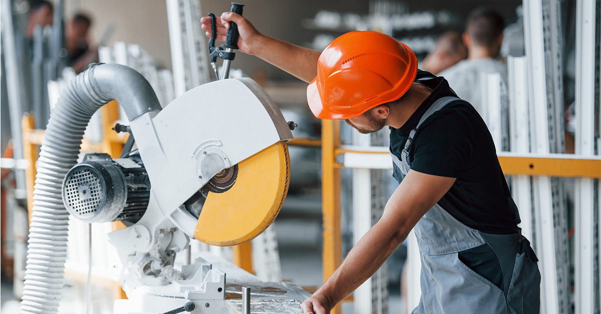 Un trabajador ajusta una máquina industrial con la ayuda de una herramienta 