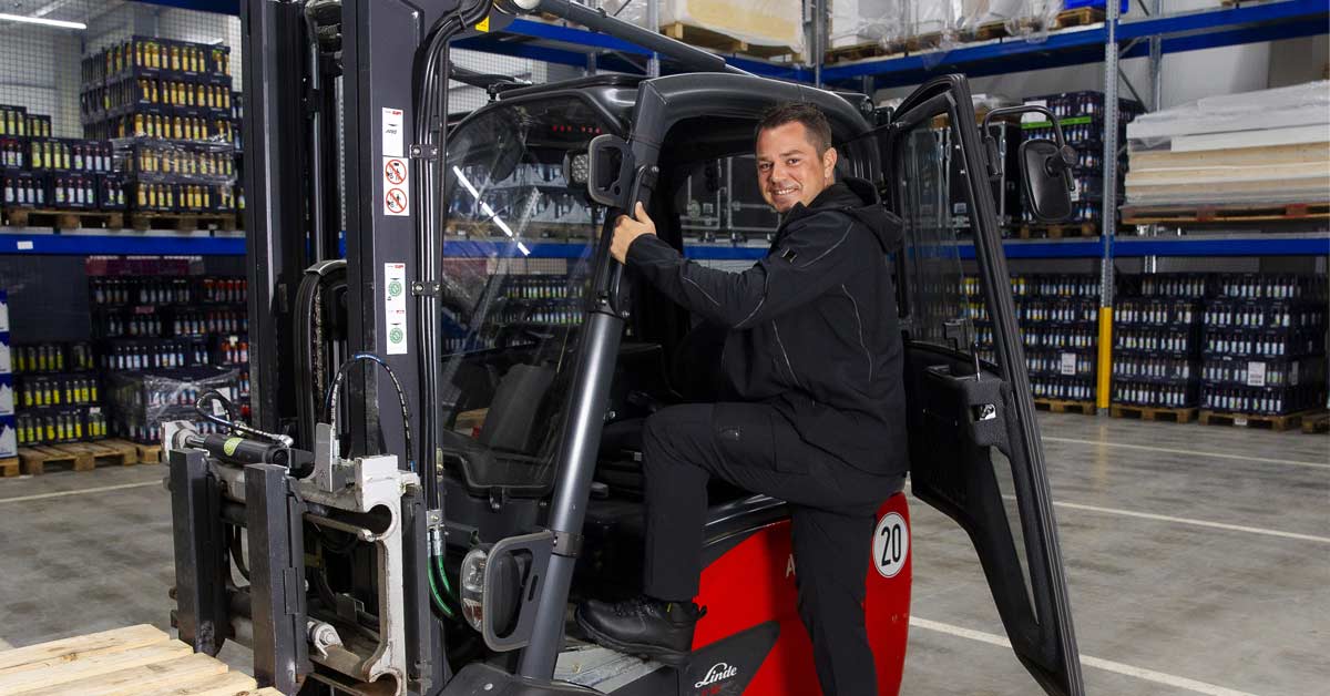 Warehouse worker climbing into the driver’s seat of a forklift