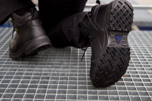 Manufacturing worker bending down on grate in Guard Mid style