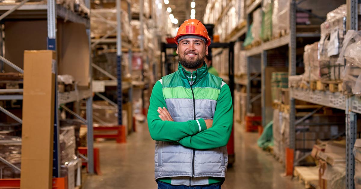 Warehouse worker posing in an aisle with storage shelves and boxes