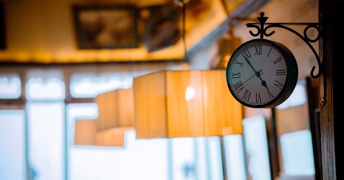 A clock hanging in a busy cafe, time to optimise staff scheduling