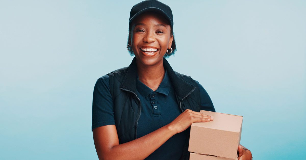 Smiling delivery driver in uniform holding a stack of small boxes