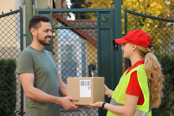 Homme recevant un colis de la part d’une livreuse à pied 