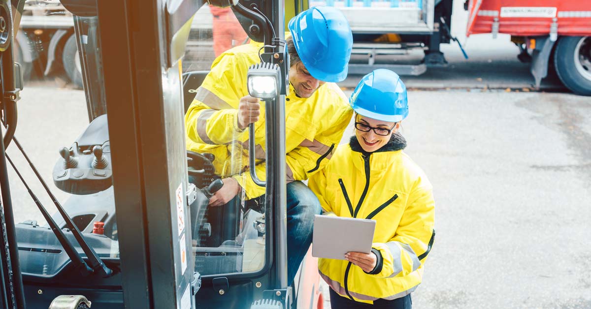 Worker and manager reviewing a slips, trips and falls risk assessment checklist behind a forklift