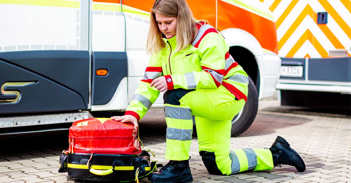 Ambulancière agenouillée près de son matériel équipée de chaussures de sécurité Defense Mid