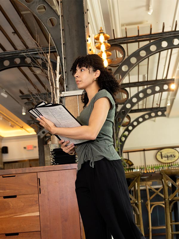 Travailleuse saisonnière en charge de l’accueil des clients dans un restaurant