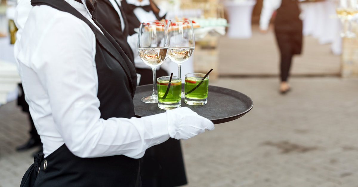 Camareros profesionales uniformados sirven comida y bebida durante un servicio de catering