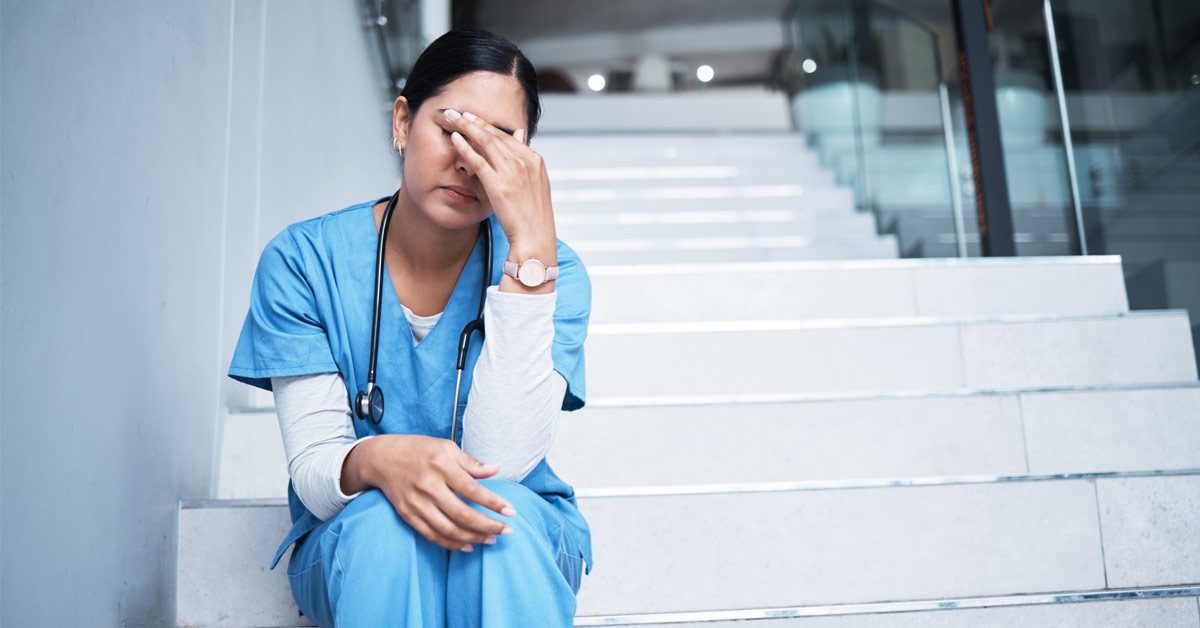 Infirmière en état de stress assise dans les escaliers de l’hôpital
